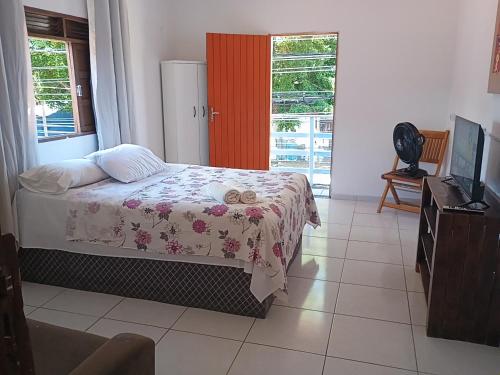 a bedroom with a bed and a tv and a window at Flats Mundos Golfinhos in Pipa
