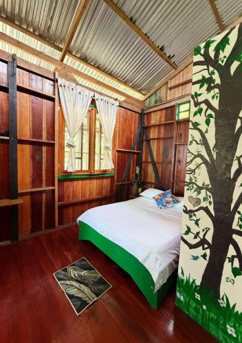 a bedroom with a bed with a tree painted on it at Playa Verde Lodge in Bahía Solano