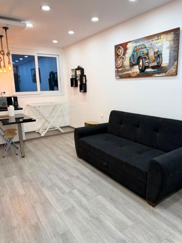 a living room with a black couch and a desk at Elegant Studio - Ideal for Couples in Mazagran
