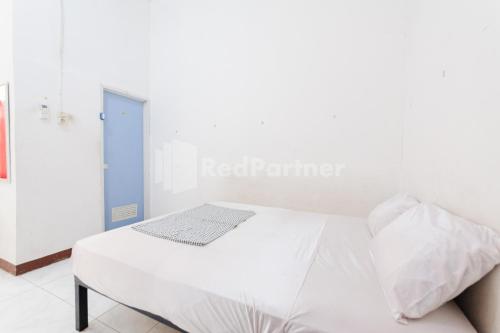a white bed in a white room with at Ombai Guest House 27 Syariah Mitra RedDoorz in Kertapati
