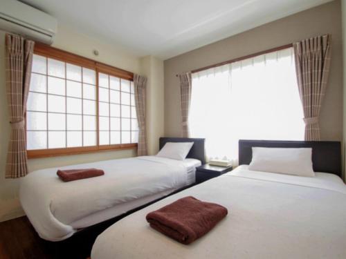 two beds in a room with two windows at ホテルリブマックスBudget川崎大師 in Kawasaki