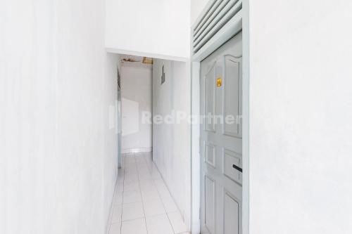 a hallway with white walls and a white door at Hotel Idayu Natuna Palembang RedPartner in Palembang