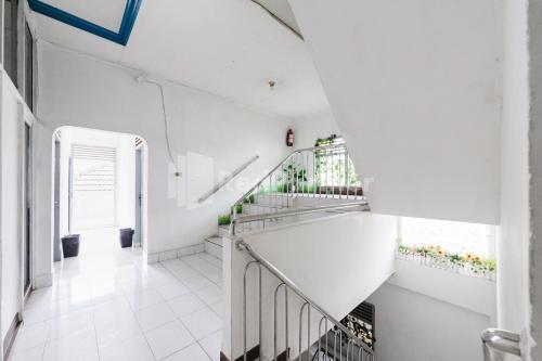 a staircase in a building with white walls and white floors at Hotel Idayu Natuna Palembang RedPartner in Palembang