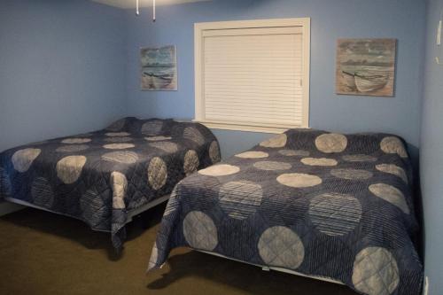 2 Betten in einem Zimmer mit blauen Wänden und einem Fenster in der Unterkunft Put-in-Bay Condos in Put-in-Bay