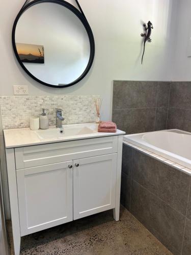 a bathroom with a sink and a mirror and a tub at Birdys Retreat in Rarotonga