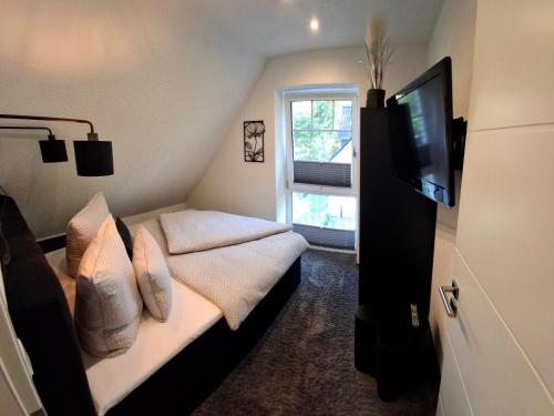 a bedroom with a bed with pillows and a television at Ferienhaus Strandnah - Ostseeurlaub in Glowe in Top-Lage in Glowe