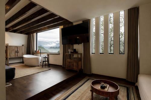 a living room with a large window and a bath tub at NINE PEAKS in Jiuzhaigou
