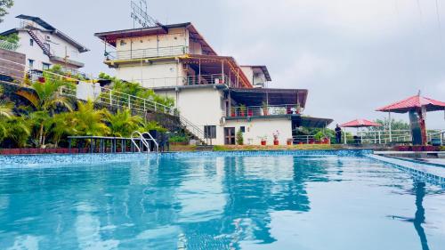 a swimming pool in front of a building at Nature's Glory Resort in Panchgani