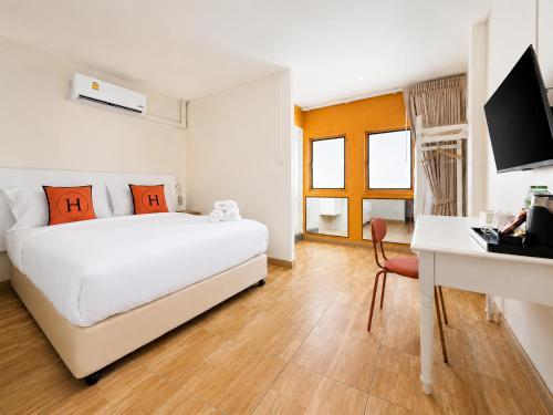 a bedroom with a bed and a desk with a computer at Horange Phuket Town in Phuket