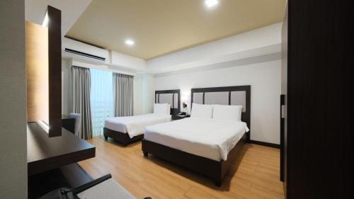 a hotel room with two beds and a television at Widus Hotel Clark in Clark