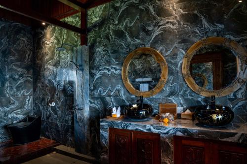 a bathroom with three mirrors on a stone wall at Grand Campuhan in Tegalalang