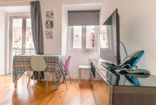 een woonkamer met een televisie en een tafel met stoelen bij Apartamento Mártires da Pátria in Lissabon