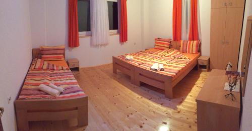 2 Betten in einem Zimmer mit roten Vorhängen in der Unterkunft Baba I Dede in Galičnik
