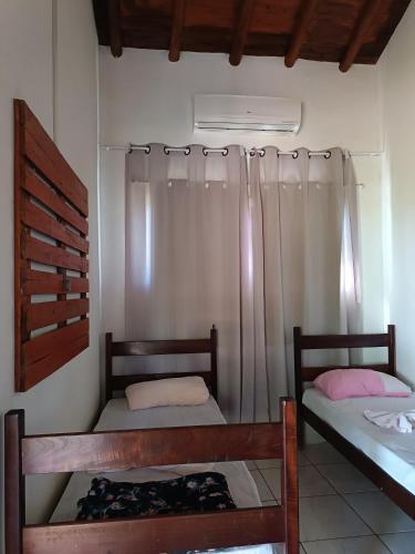a bedroom with two beds and a window with curtains at Hotel E Pousada do Patrão in Bataguaçu