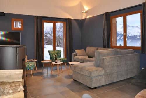 a living room with a couch and a tv at Chalet Rouge ou Blanc in Villard-Reculas