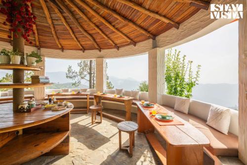 a living room with a wooden table and benches at StayVista at Sukoon Nature Retreat in Bhatrojkhan
