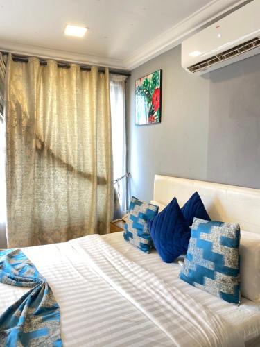 a bedroom with a bed with blue and white pillows at Peach City Hotel in Prampram