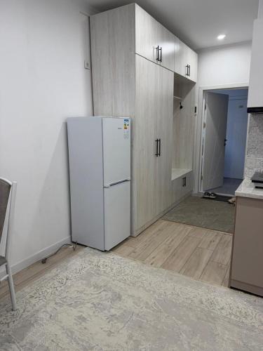 an empty kitchen with a white refrigerator and cabinets at Квартира студия in Bosteri