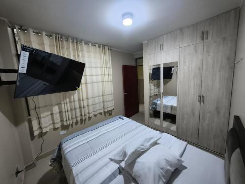 a bedroom with a bed and a flat screen tv at Esencia de Altura Hostal in El Tambo