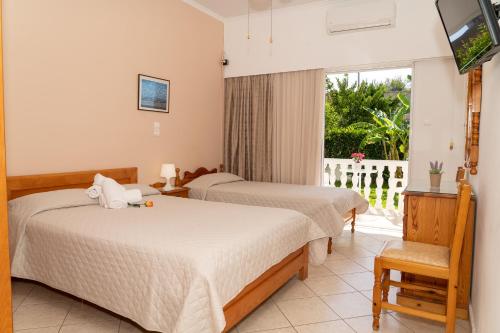 a hotel room with two beds and a balcony at Posidonia Pension in Amarynthos