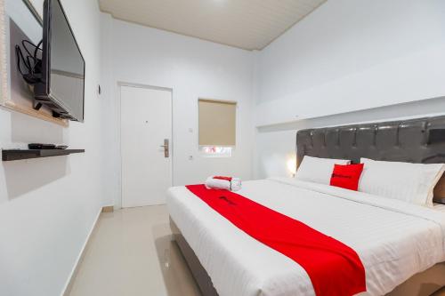 a bedroom with a large bed with a red blanket at RedDoorz Plus near Palembang Icon Mall 2 in Palembang