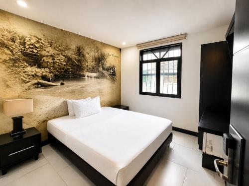 a bedroom with a bed and a painting on the wall at Hotel Habitat San Antonio in Cali