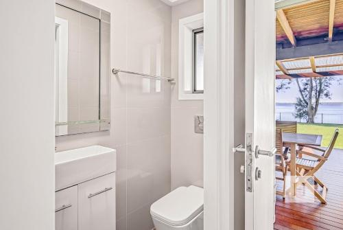 a white bathroom with a toilet and a table at Sunrise Waters in Gorokan