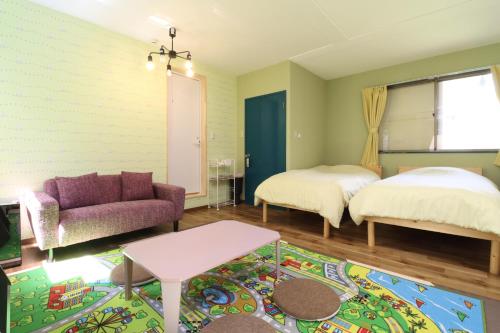a living room with a couch and a bed and a rug at ボウケンノモリささぐり in Sasaguri