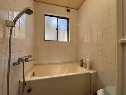 a bath tub in a bathroom with a window at ボウケンノモリささぐり in Sasaguri