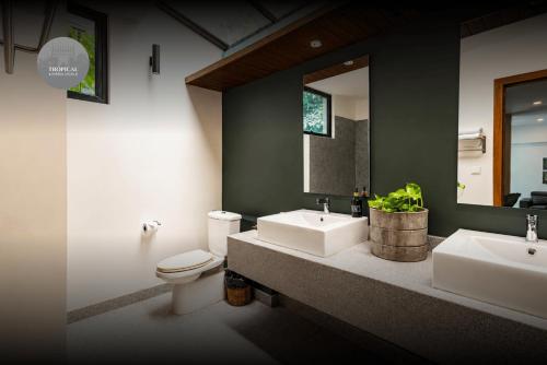 a bathroom with two sinks and a toilet and a mirror at Tropical Garden House in Siem Reap