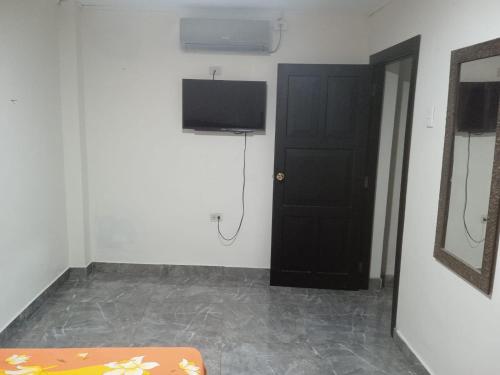 a room with a black door and a television at Hospedaje Hotel Chone in Chone