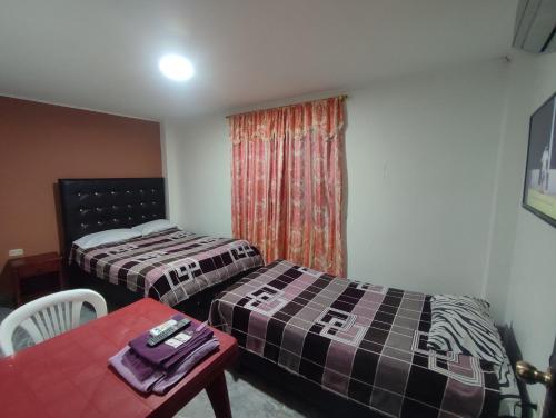 a room with two beds and a table and a window at Hospedaje Hotel Chone in Chone