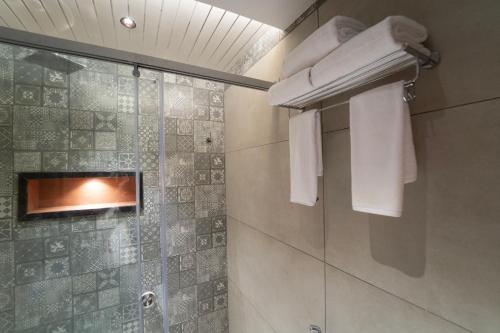 a bathroom with a shower with towels on a wall at PSR Coral Resorts, 800m Away from Rameswaram Temple in Rāmeswaram