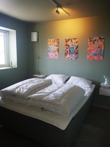 a bed in a bedroom with paintings on the wall at Lofoten Seaview Apartment B in Sennesvik