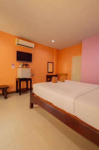 a bedroom with a large white bed and orange walls at ไข่มุกรีสอร์ทเกาะล้าน in Ko Larn