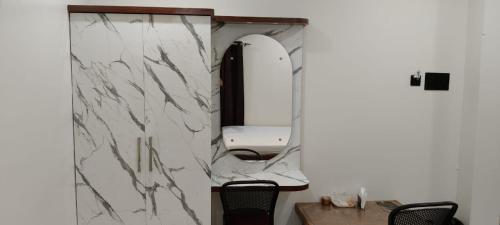 a white marble bathroom with a mirror and chairs at The Highway Haven in Silchar