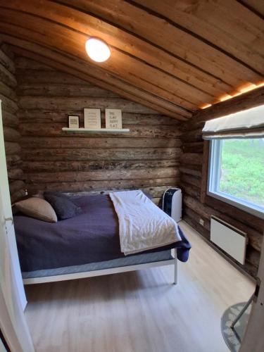 a bedroom with a bed in a log cabin at Iso-Syöte tunnelmallinen kelomökki in Naamanka