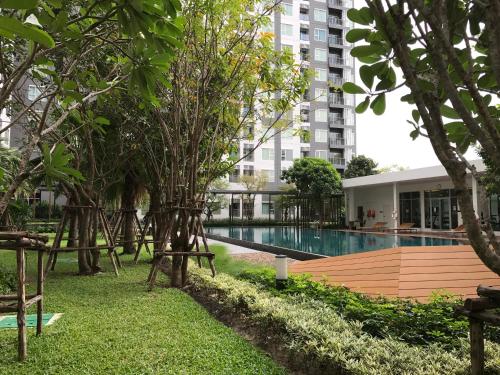 a swimming pool in a park with trees and a building at Apartment Rattanatibet in Nonthaburi