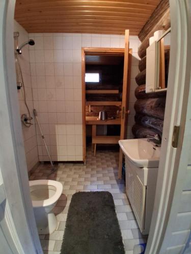 a small bathroom with a toilet and a sink at Iso-Syöte tunnelmallinen kelomökki in Naamanka