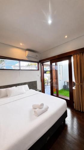 a bedroom with a large white bed with a large window at Sutji living in Sanur