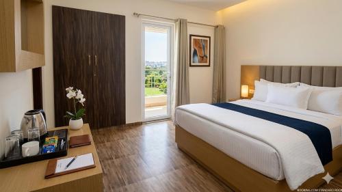 a hotel room with a large bed and a window at JHS Kundli in Sonīpat