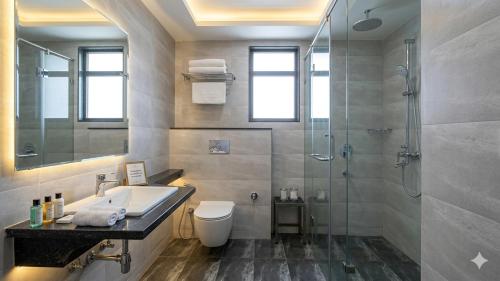 a bathroom with a shower and a sink and a toilet at JHS Kundli in Sonīpat
