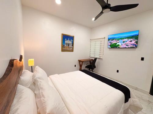 a bedroom with a white bed and a ceiling fan at La Casona Suchitoto in Suchitoto