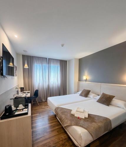 a hotel room with two beds and a desk at AZZ Valencia Táctica Hotel in Paterna