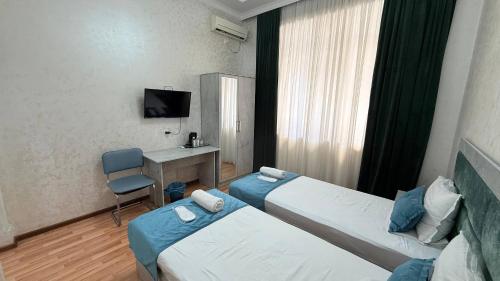 a hotel room with two beds and a desk at Art inn hotel in Tashkent