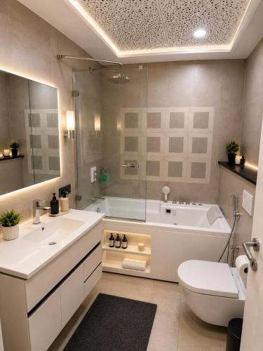 a bathroom with a tub and a sink and a toilet at Whispers above the city 2Bhk Centaurus Mall pool Gym City view in Islamabad