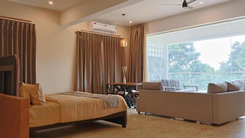 a bedroom with a bed and a couch and a window at Aadvik Luxury Farmstay in Antarasante
