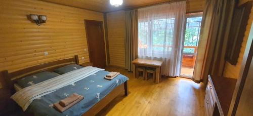a bedroom with a bed and a table and a window at Над Річкою in Yaremche