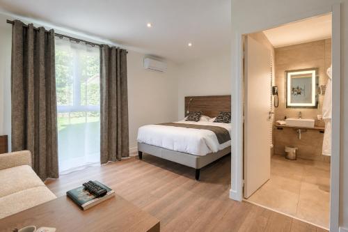 a bedroom with a bed and a sink at Logis Hotel Le Petit Casset in La Boisse