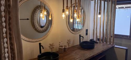 a bathroom with three mirrors and a wooden counter at Meno Lagoon Bungalows in Gili Meno